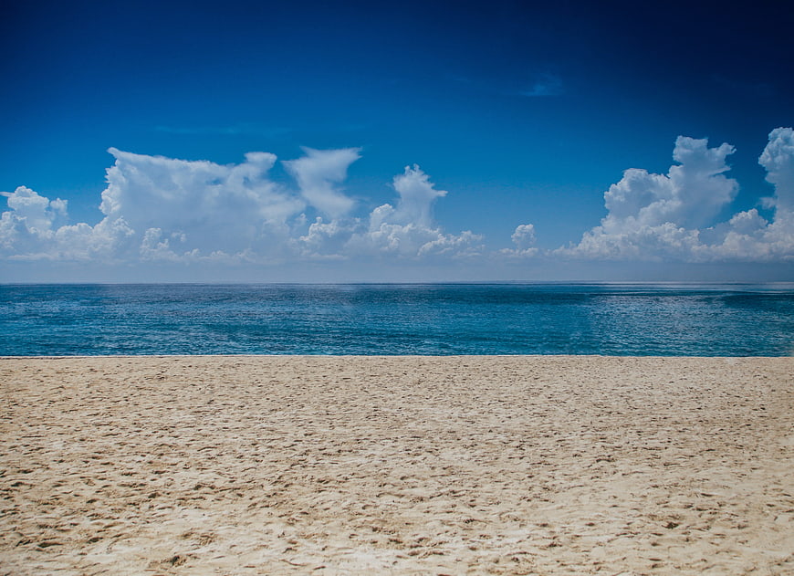 Serene tropical beach with blue sky and white clouds