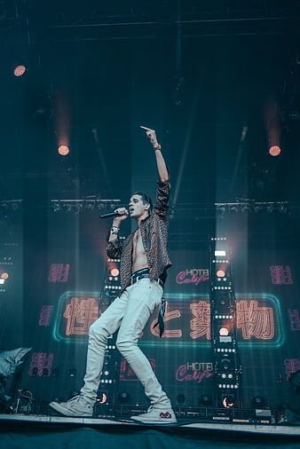 Male Singer Performing Energetically on Stage with Neon Lights