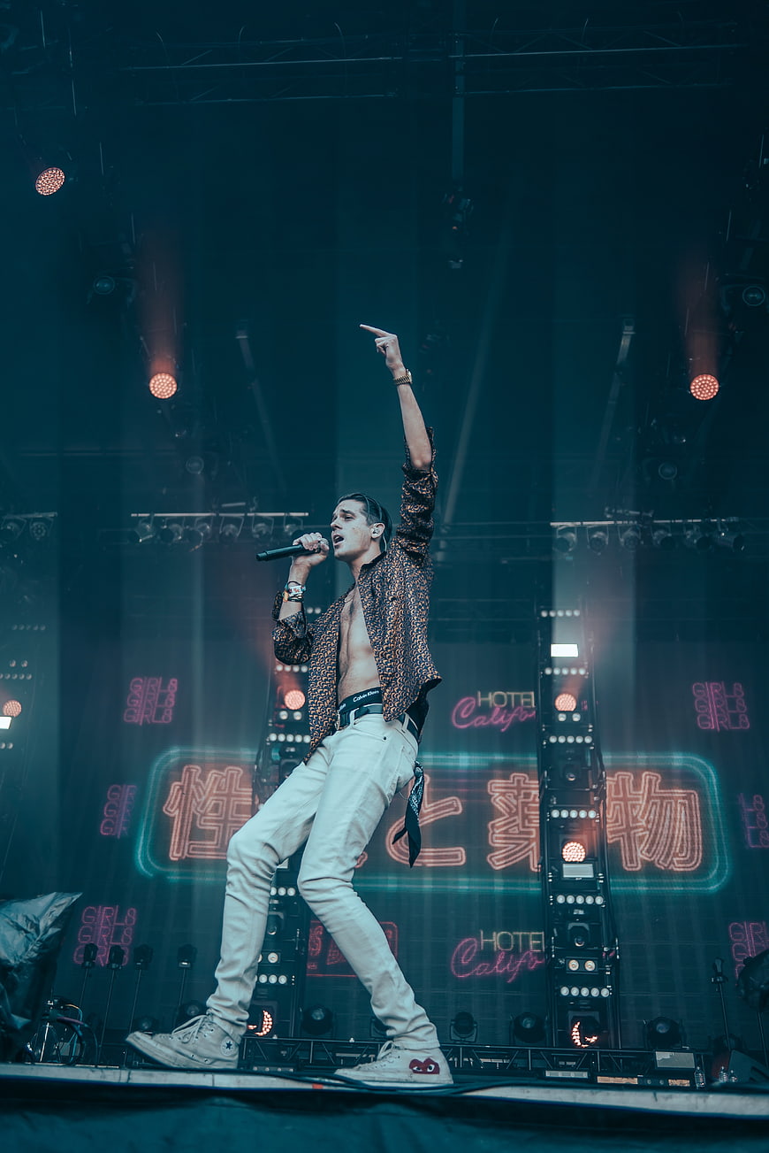 Male Singer Performing Energetically on Stage with Neon Lights