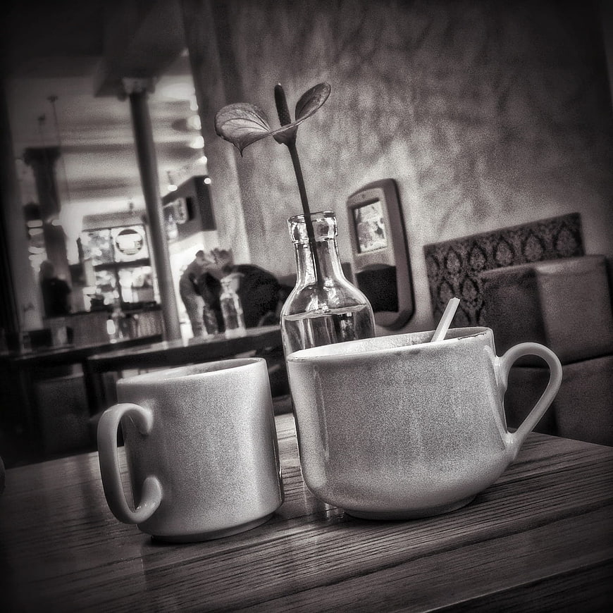 Two ceramic coffee mugs on a wooden table in a cafe