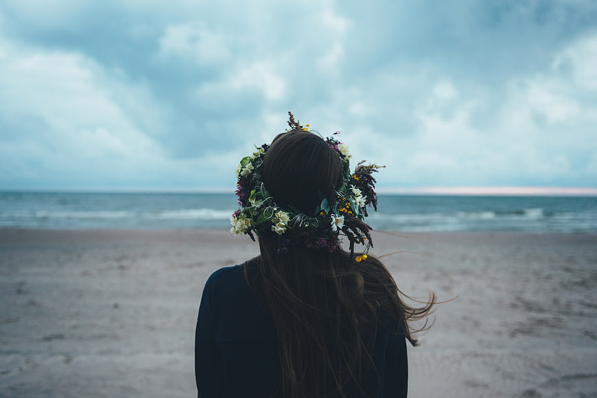 Woman with Flower Crown on Beach Looking at Ocean