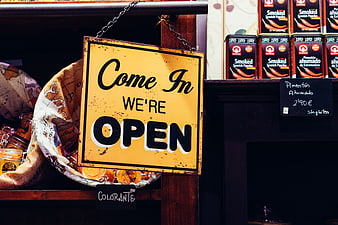 Vintage yellow 'Come In We're Open' sign hanging in a shop