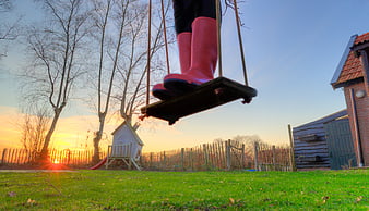 Child in Pink Boots on Swing at Sunset