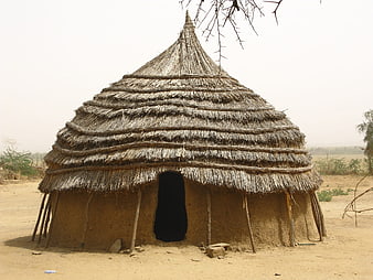 Traditional Thatched Mud Hut In Rural African Village Landscape