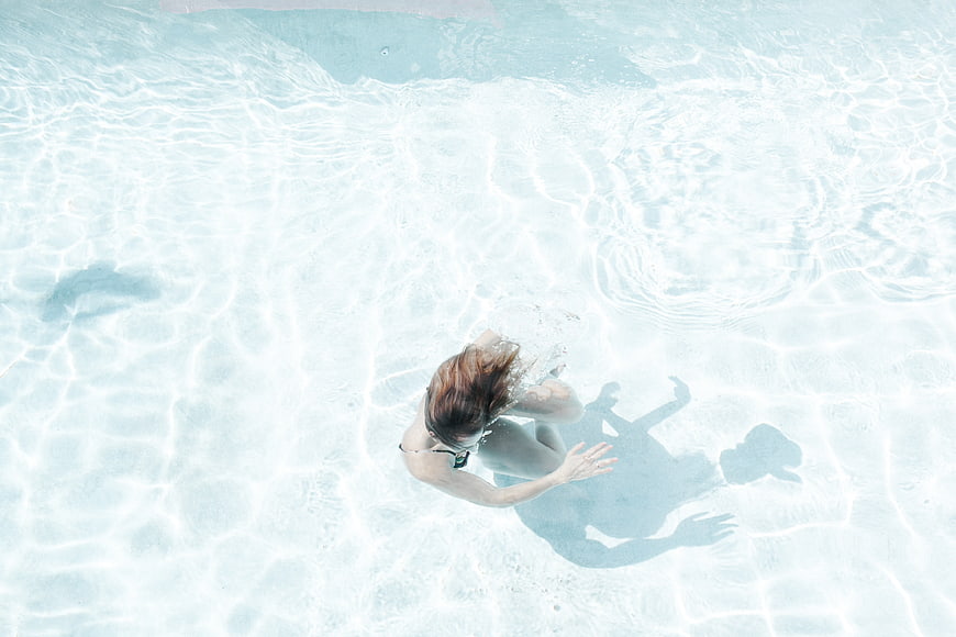 Aerial view of woman swimming in clear blue pool