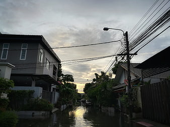 Flooded residential street with houses and power lines at dawn