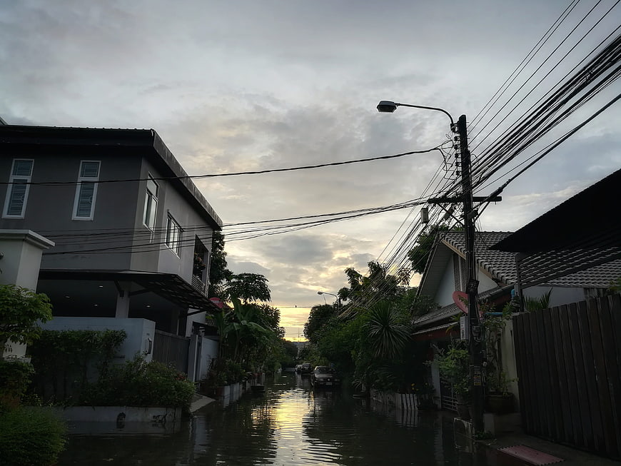 Flooded residential street with houses and power lines at dawn