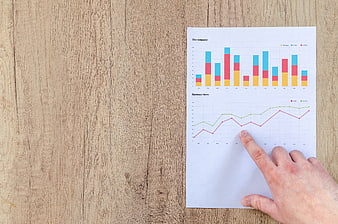 Hand pointing at business growth charts on wooden desk