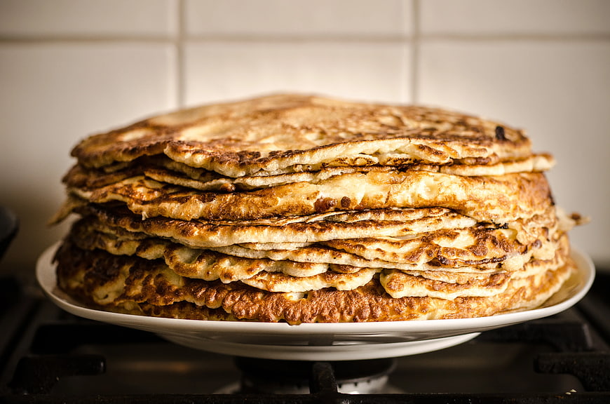 Stack of golden homemade pancakes on a white plate