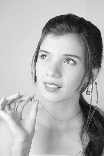 Black and white portrait of a young woman holding a delicate necklace