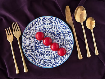 Flat lay of blue patterned plate with tomatoes and gold cutlery