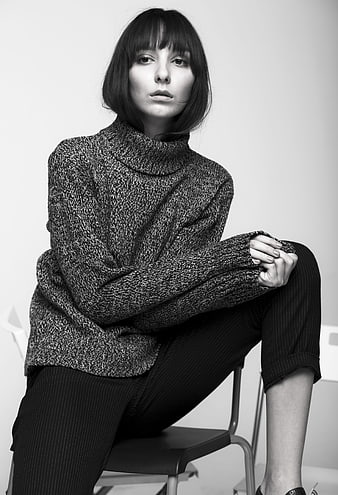 Black and white studio portrait of a young woman in a knitted turtleneck