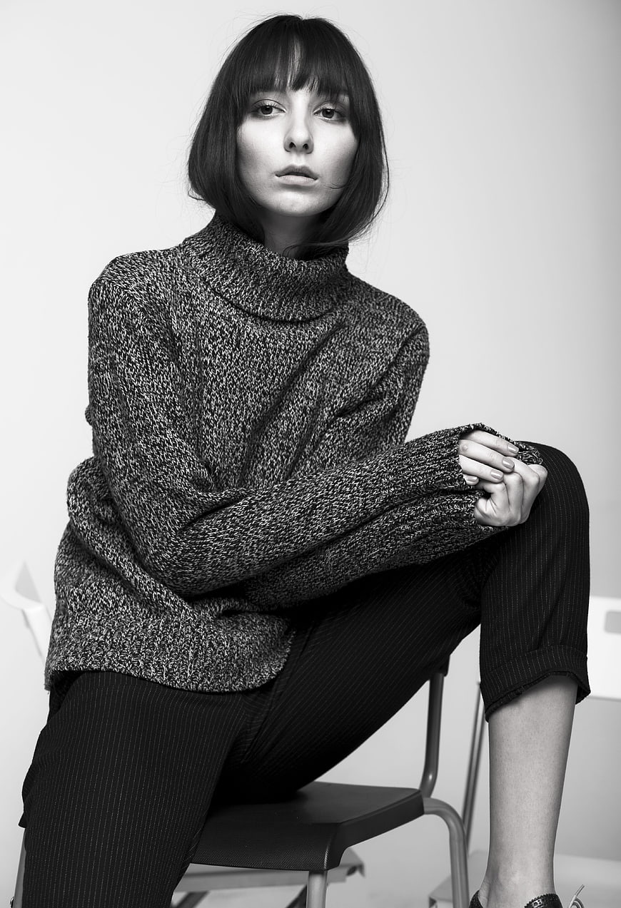 Black and white studio portrait of a young woman in a knitted turtleneck
