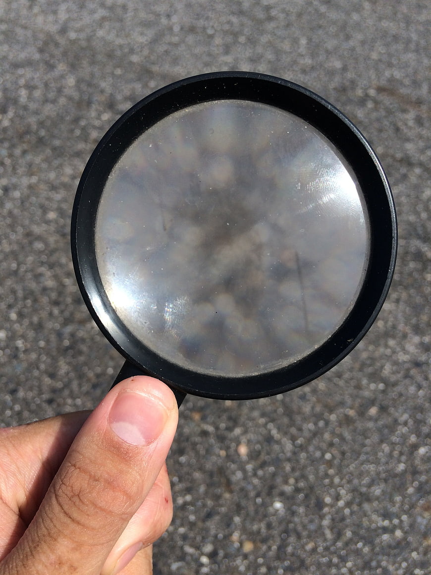Hand holding magnifying glass over asphalt texture