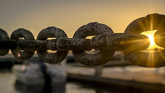 Rusty Chain Links Silhouetted Against Golden Sunset Sunburst
