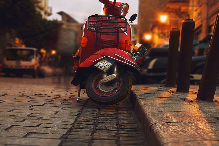 Rear View of Classic Red Scooter on Cobblestone Street