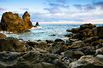 Dramatic Rocky Coastline with Ocean Waves and Cloudy Sky