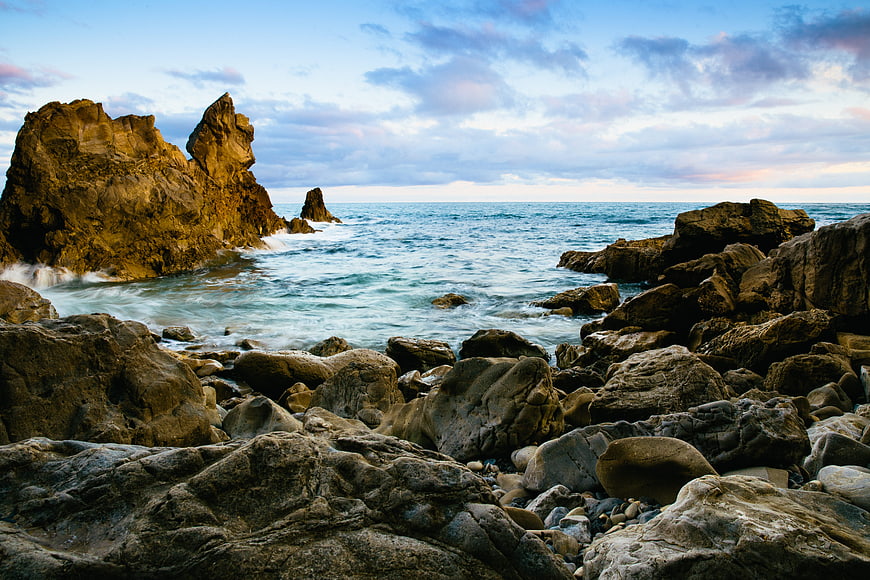 Dramatic Rocky Coastline with Ocean Waves and Cloudy Sky