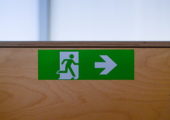 Green emergency exit sign on wooden wall