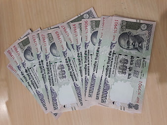 Fan of Indian 100 Rupee Notes on Wooden Table