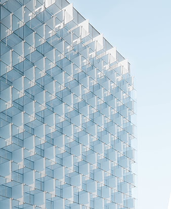 Modern glass building facade with geometric pattern and blue sky