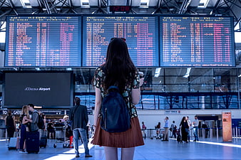 Woman Checking Flight Departure Board at Airport Terminal