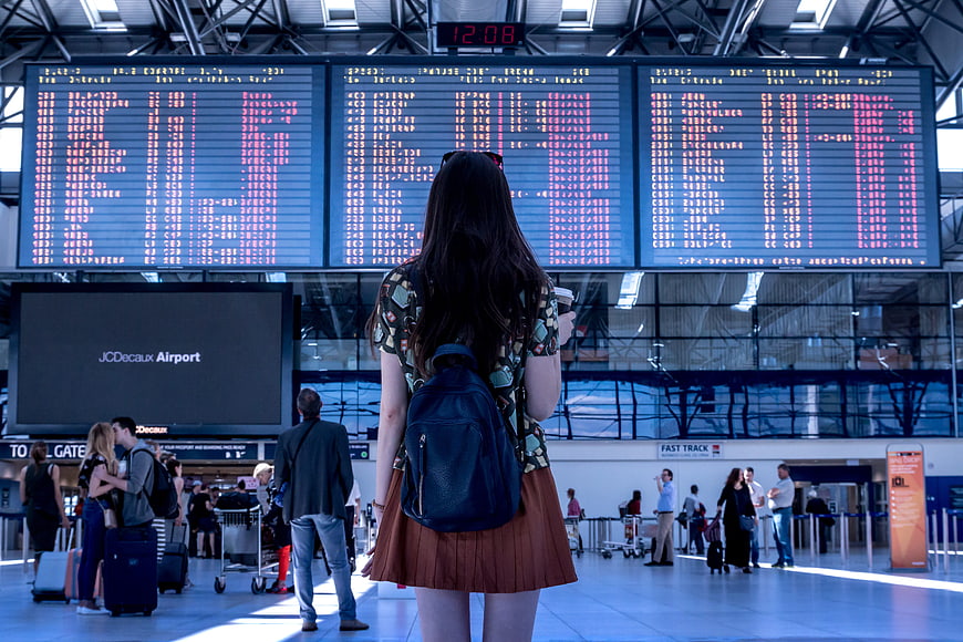 Woman Checking Flight Departure Board at Airport Terminal