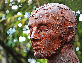 Rusty metal sculpture of a human head in profile