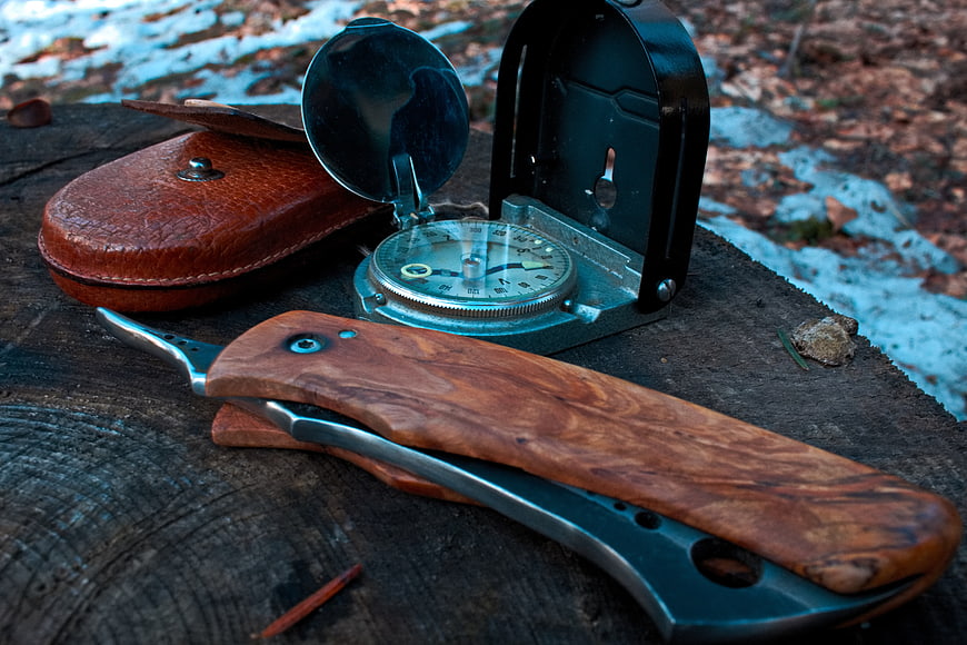 Vintage Compass and Wooden Knife on Tree Stump in Winter Forest