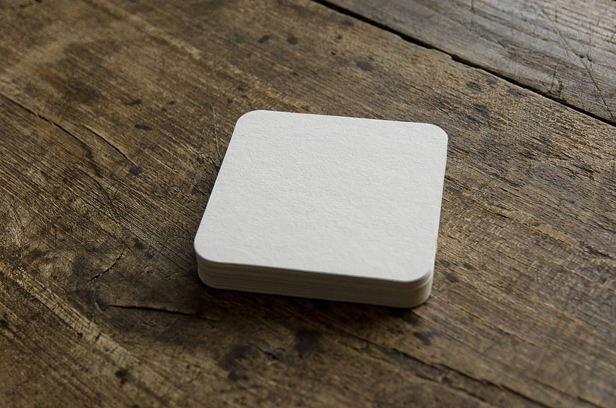 Blank White Paper Coaster Stack Mockup on Rustic Wooden Table