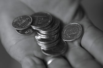 Black and white close-up of coins held in an open human hand