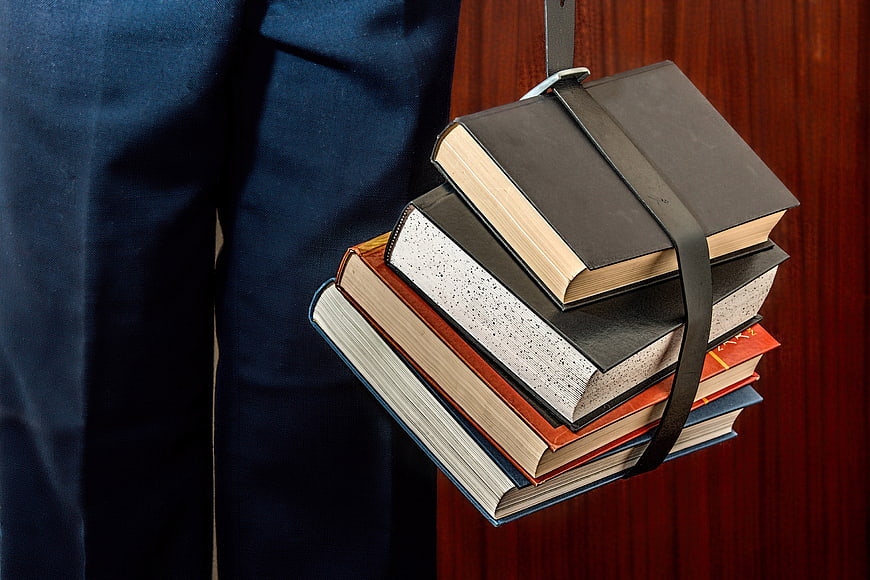 Stack of Books Held by Student in Blue Uniform