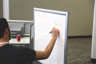 Man sketching business strategy on whiteboard in modern office
