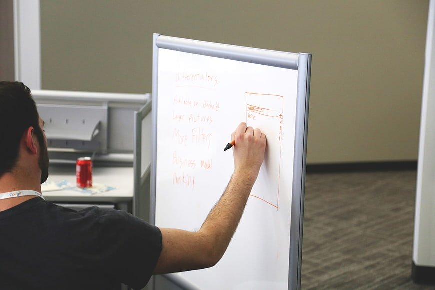 Man sketching business strategy on whiteboard in modern office