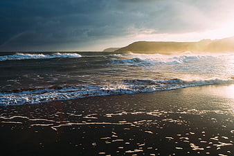 Dramatic Sunset Over Black Sand Beach with Crashing Waves