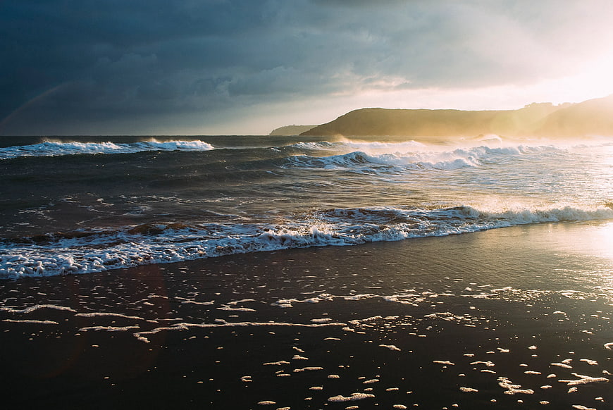 Dramatic Sunset Over Black Sand Beach with Crashing Waves