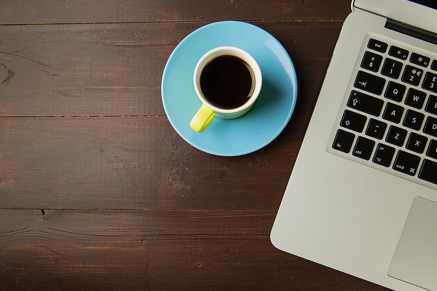 Top View of Coffee Cup and Laptop on Wooden Desk