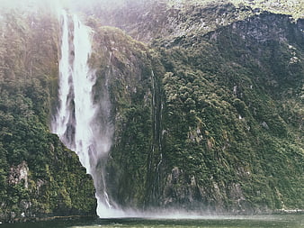 Majestic waterfall cascading down lush green mountain cliff