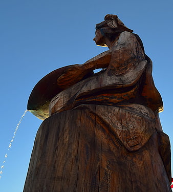 Low angle view of wooden fountain sculpture against blue sky