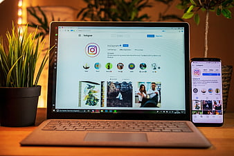 Laptop and Smartphone Displaying Instagram Interface on Wooden Desk