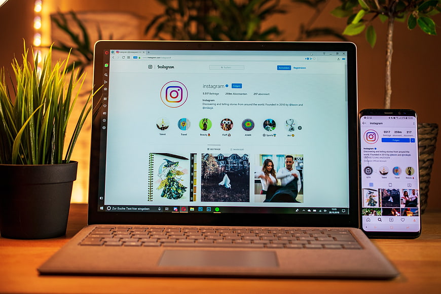 Laptop and Smartphone Displaying Instagram Interface on Wooden Desk