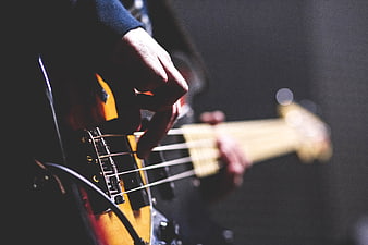 Close-up of hands playing electric bass guitar on stage