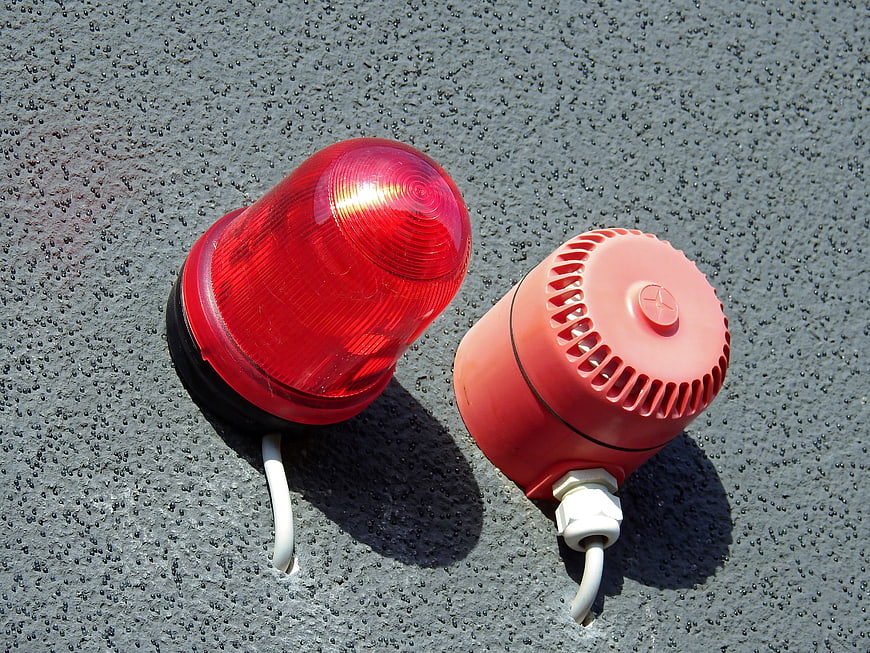 Red emergency warning light and siren on textured wall