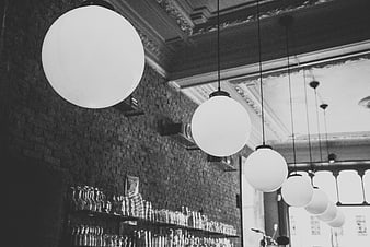 Black and white interior of a bar with hanging globe lights