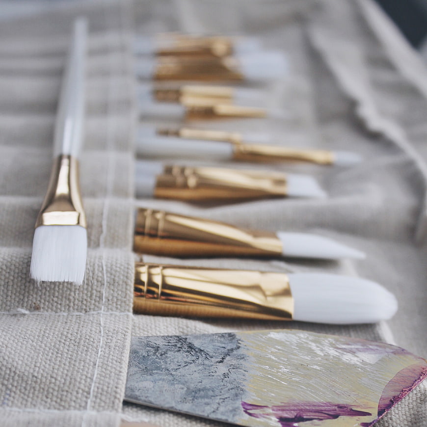 Gold and White Paint Brushes on Canvas with Palette Knife
