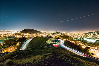 Night long exposure of winding road with city lights and stars
