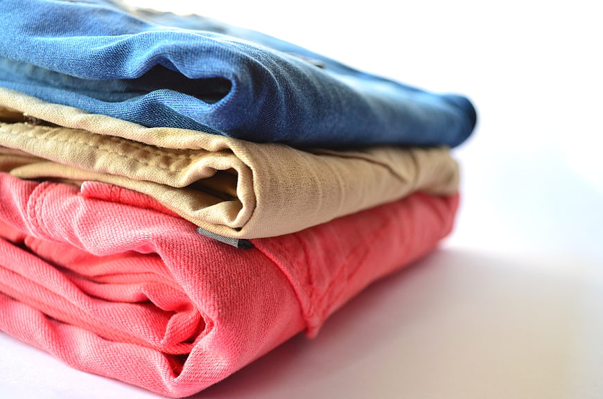 Stack of folded colorful pants on white background