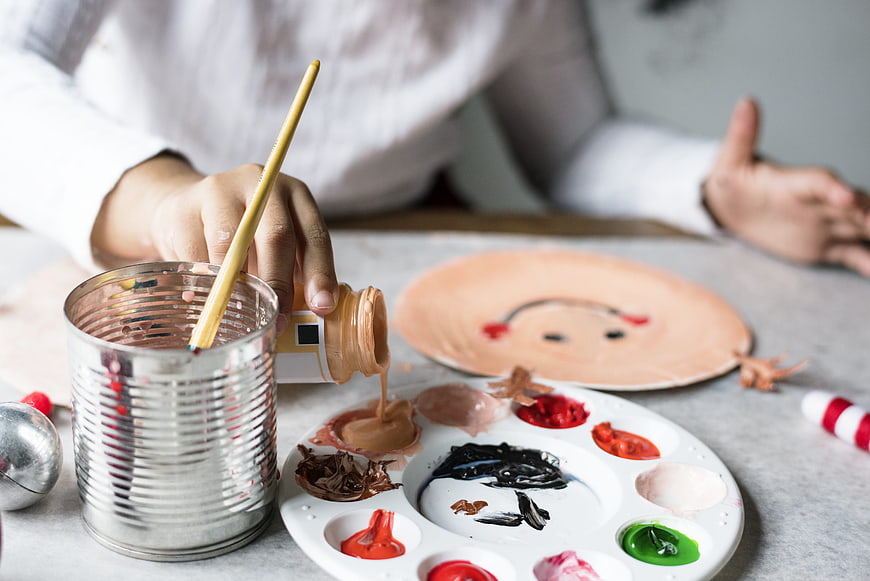 Child pouring paint on palette for arts and crafts