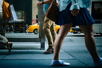 Low angle shot of people walking on busy city street with yellow taxi