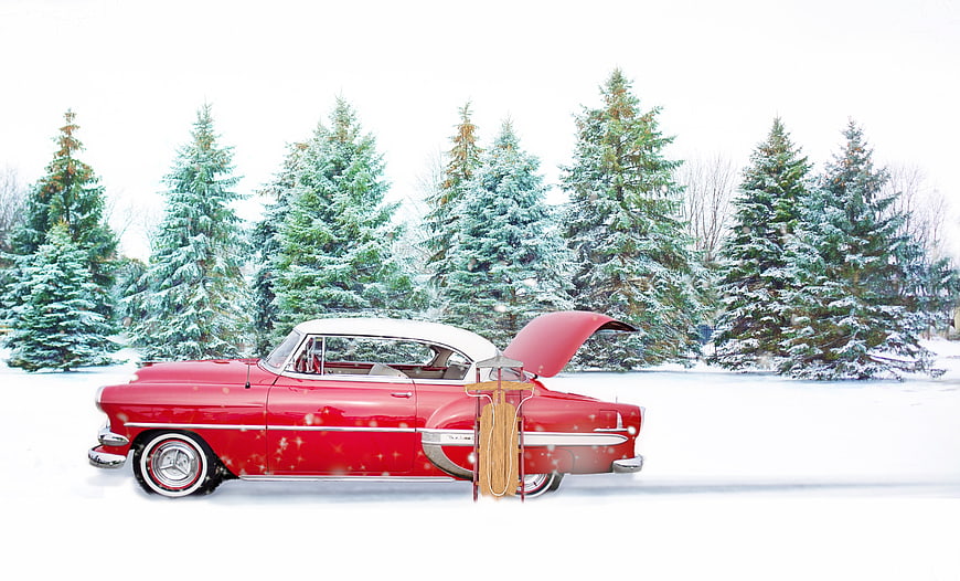 Red Vintage Car with Sled in Snowy Pine Forest